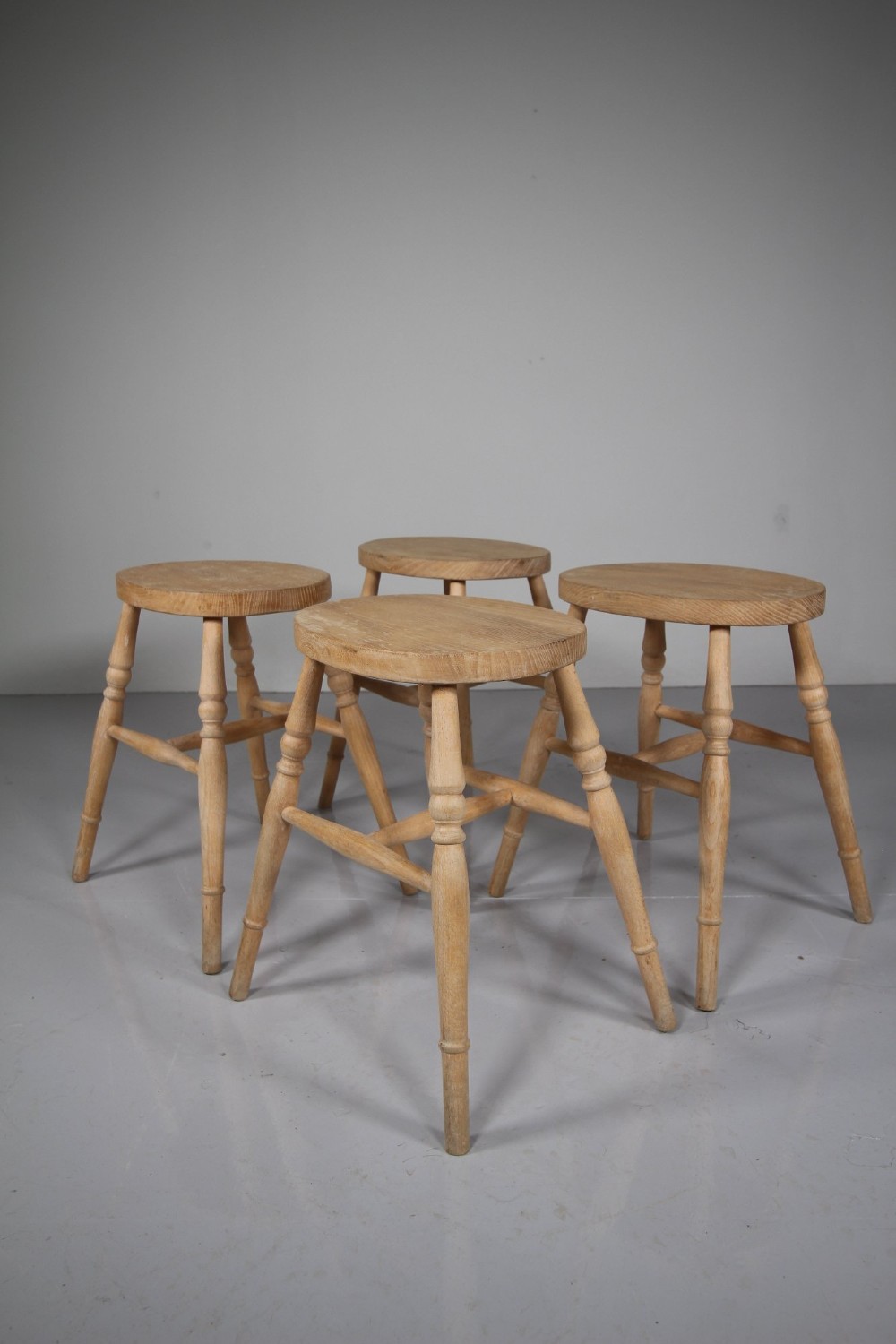 A set of four Edwardian natural wood dining stools featuring oval seats, turned legs, and lower stretchers. View III