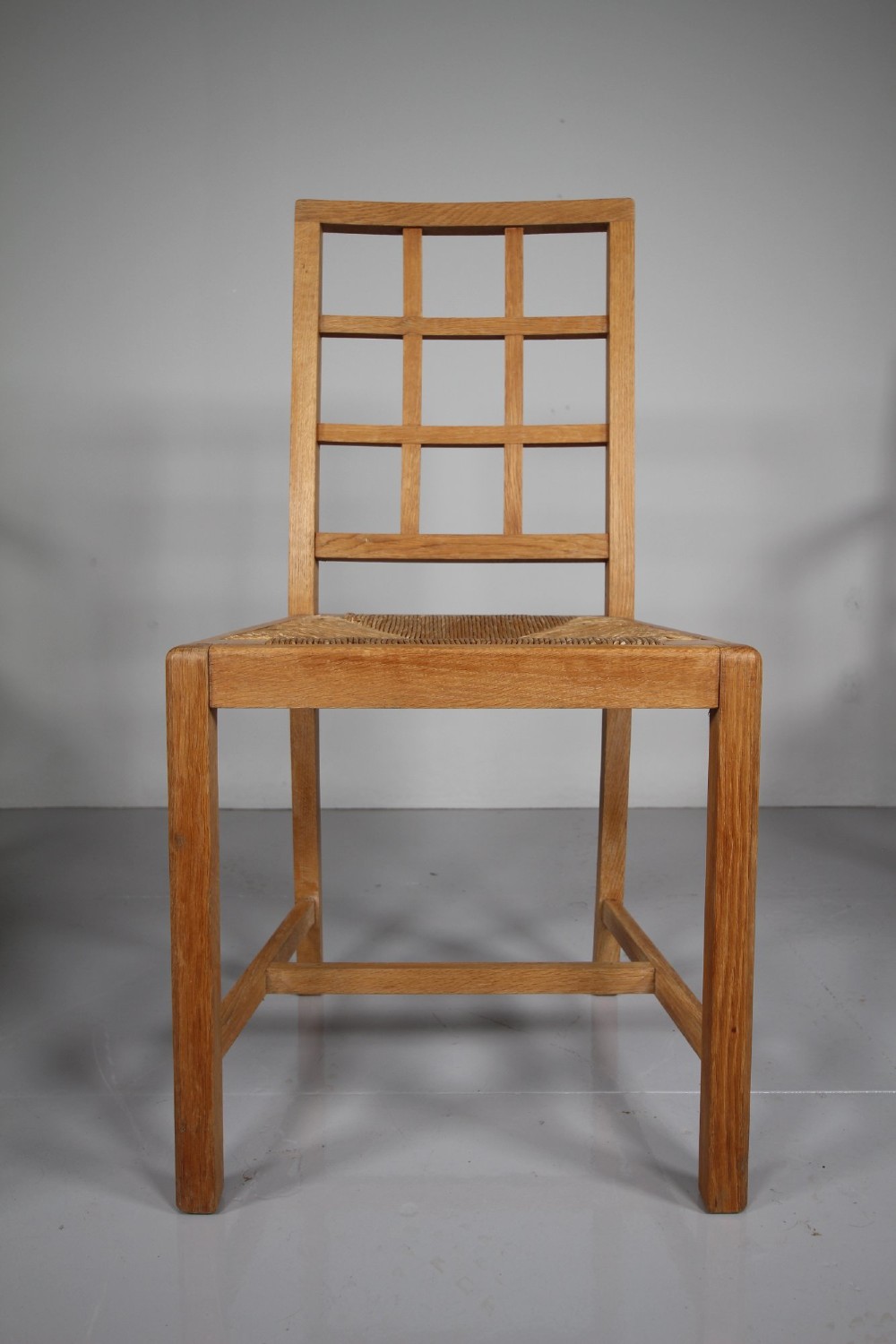 A set of six light oak 1920s dining chairs featuring geometric lattice backs, straight legs, and woven seats. View VII