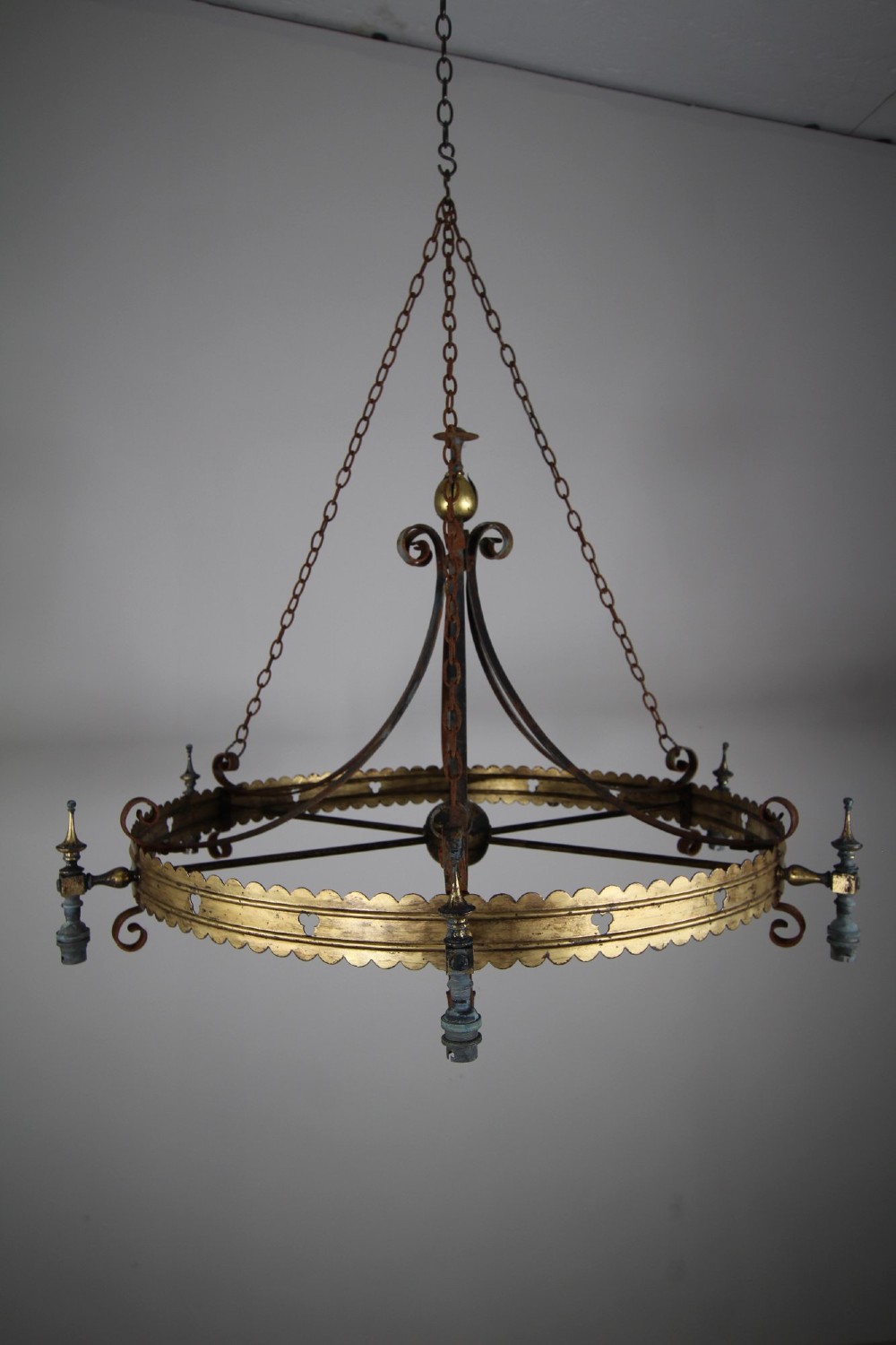 A 19th-century Gothic Revival brass and iron chandelier featuring a scalloped coronet band supported by suspension chains and curved lower scrollwork. View II