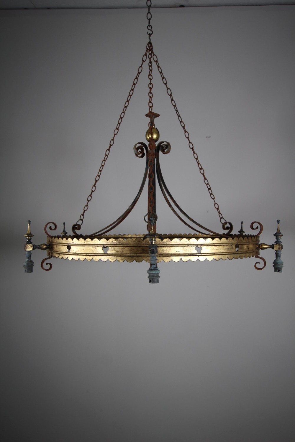 A 19th-century Gothic Revival brass and iron chandelier featuring a scalloped coronet band supported by suspension chains and curved lower scrollwork. View III