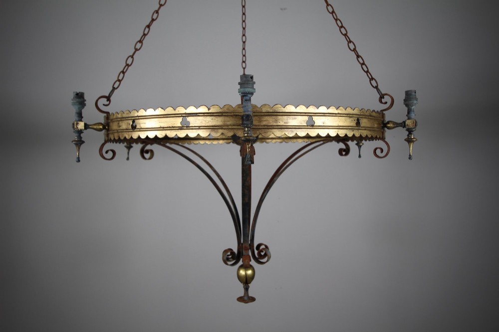 A 19th-century Gothic Revival brass and iron chandelier featuring a scalloped coronet band supported by suspension chains and curved lower scrollwork. View IV