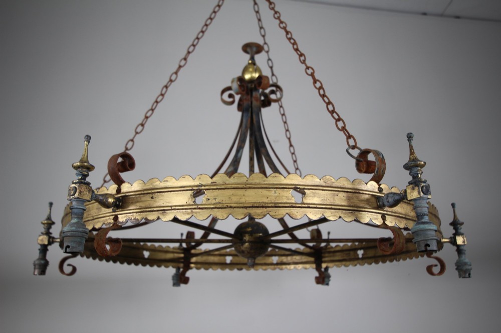 A 19th-century Gothic Revival brass and iron chandelier featuring a scalloped coronet band supported by suspension chains and curved lower scrollwork. View VI