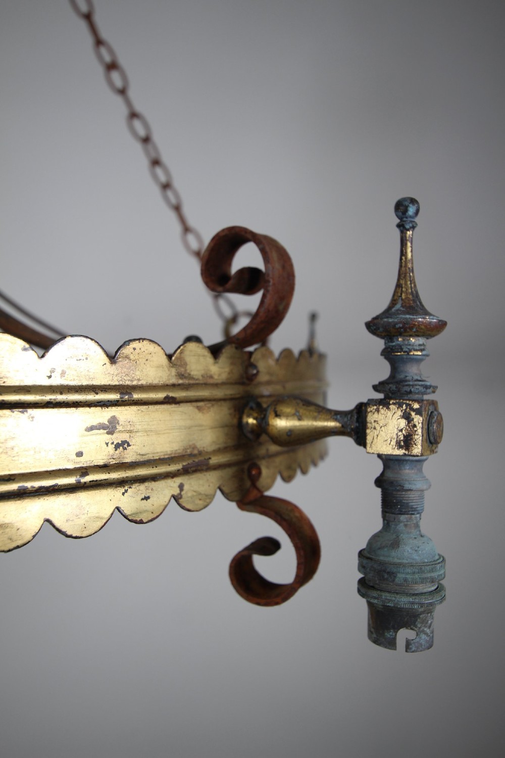 A 19th-century Gothic Revival brass and iron chandelier featuring a scalloped coronet band supported by suspension chains and curved lower scrollwork. View VIII