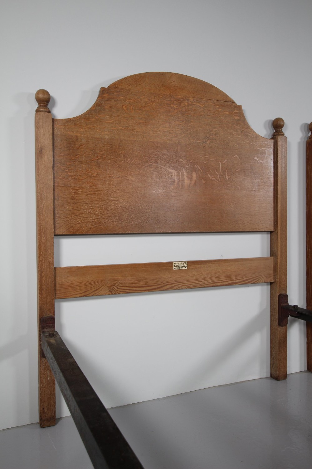A matching pair of Edwardian oak single bed frames with gentle arched headboards, simple footboards, and turned corner posts. View II