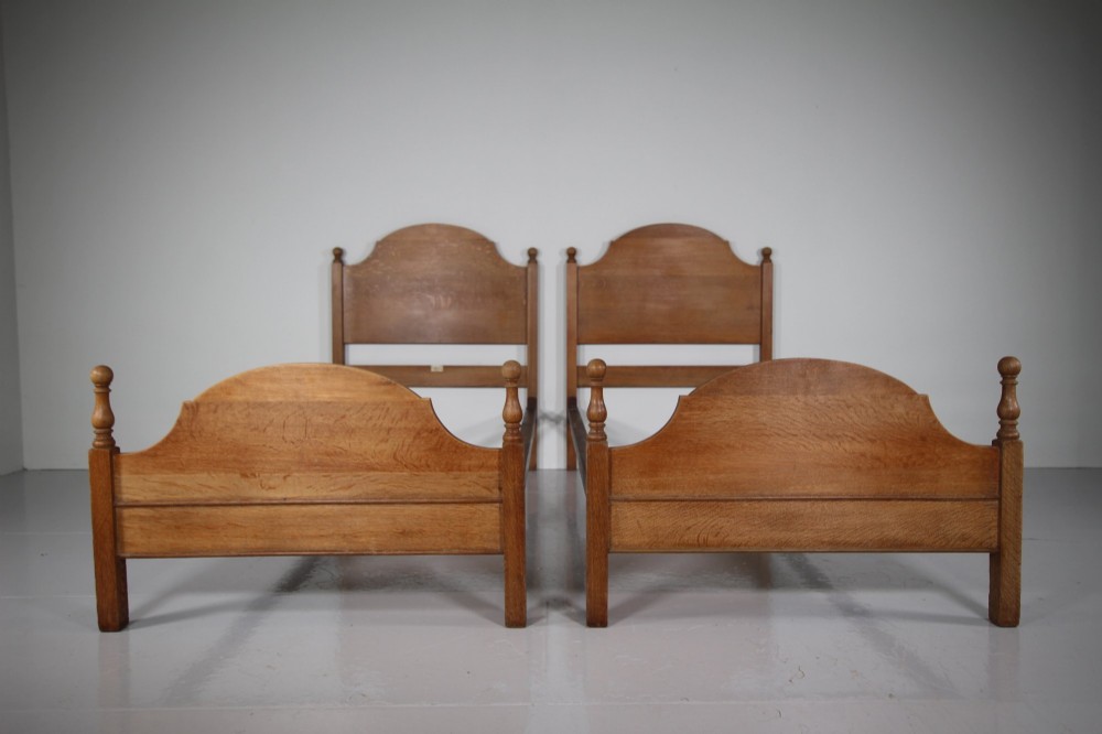 A matching pair of Edwardian oak single bed frames with gentle arched headboards, simple footboards, and turned corner posts. View III