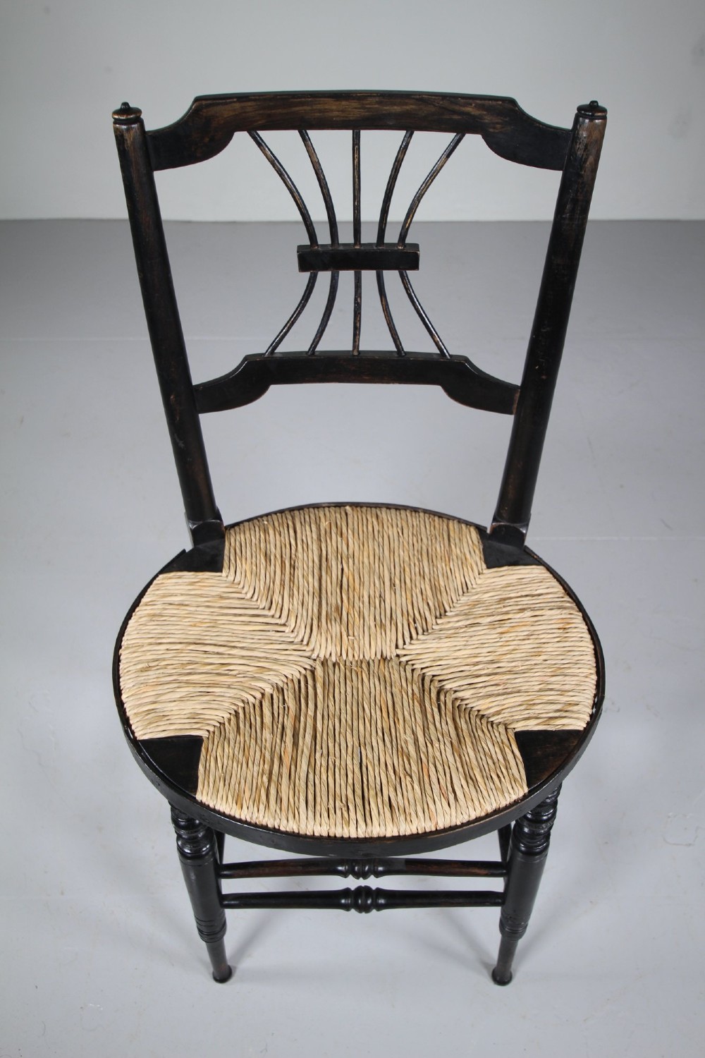 An ebonised wooden side chair with a woven rush seat, turned legs, and an intricate Rossetti splat back. View III