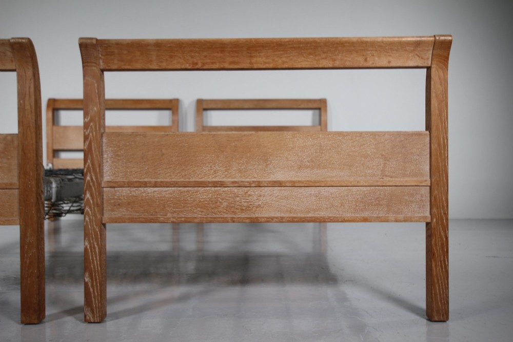 A pair of 1920s light oak single bed frames featuring curved headboards and metal spring mesh bases. View III