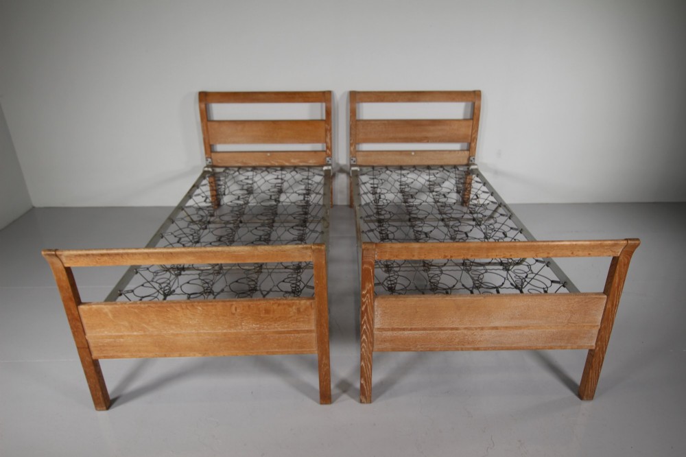 A pair of 1920s light oak single bed frames featuring curved headboards and metal spring mesh bases. View IV