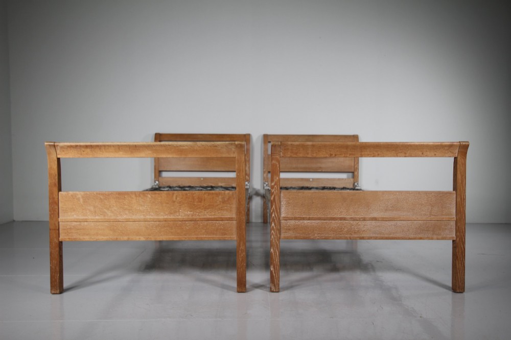 A pair of 1920s light oak single bed frames featuring curved headboards and metal spring mesh bases. View VIII