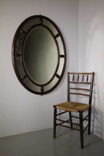 A large 19th-century oval mahogany wall mirror featuring a double-banded wooden frame with segmented antiqued glass borders. View VI