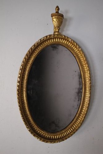 An 18th-century Neoclassical oval giltwood wall mirror featuring an urn finial top and fluted border along the carved frame. View II