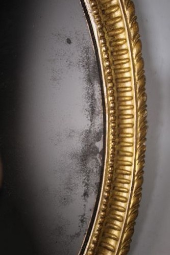 An 18th-century Neoclassical oval giltwood wall mirror featuring an urn finial top and fluted border along the carved frame. View IV