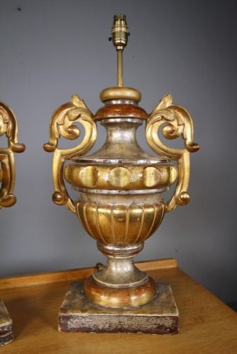 A pair of 19th-century carved pine urn table lamps with distressed gold leaf finish, scrolled handles, and square plinth bases. View V