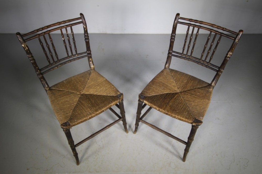 A pair of antique Regency dark painted pine side chairs featuring faux bamboo turned frames and woven rush seats. View II