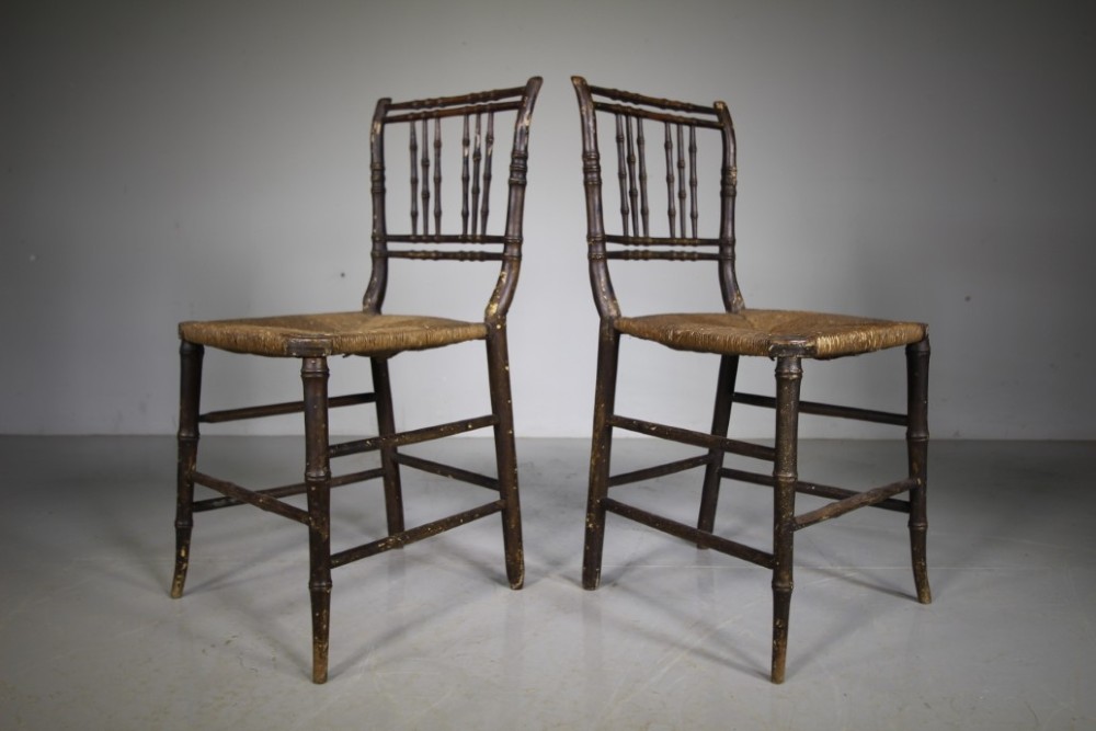 A pair of antique Regency dark painted pine side chairs featuring faux bamboo turned frames and woven rush seats. View III