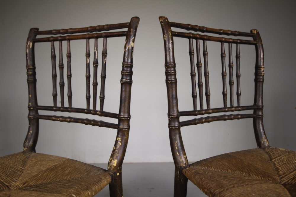 A pair of antique Regency dark painted pine side chairs featuring faux bamboo turned frames and woven rush seats. View IV