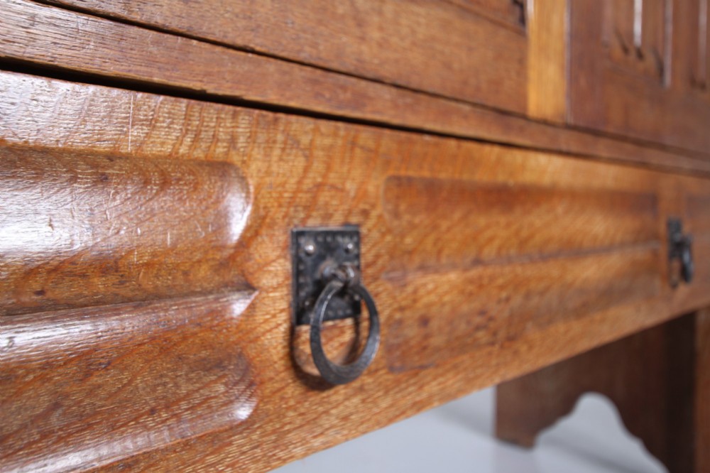 A 19th-century oak dresser base featuring two carved linenfold panel doors, iron drop handles, a single lower drawer, and carved plank supports. View II