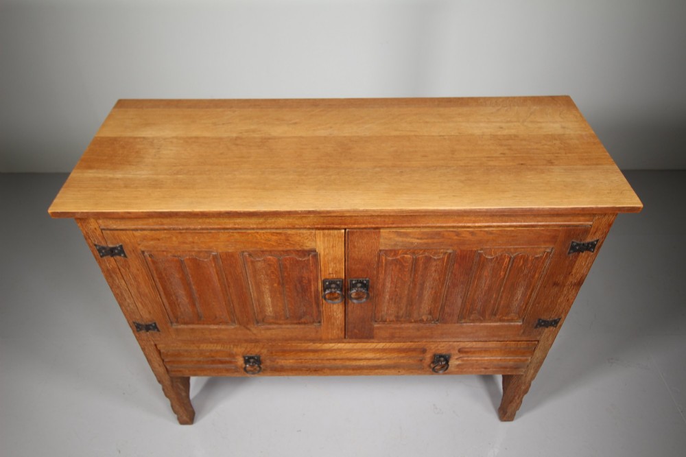 A 19th-century oak dresser base featuring two carved linenfold panel doors, iron drop handles, a single lower drawer, and carved plank supports. View III