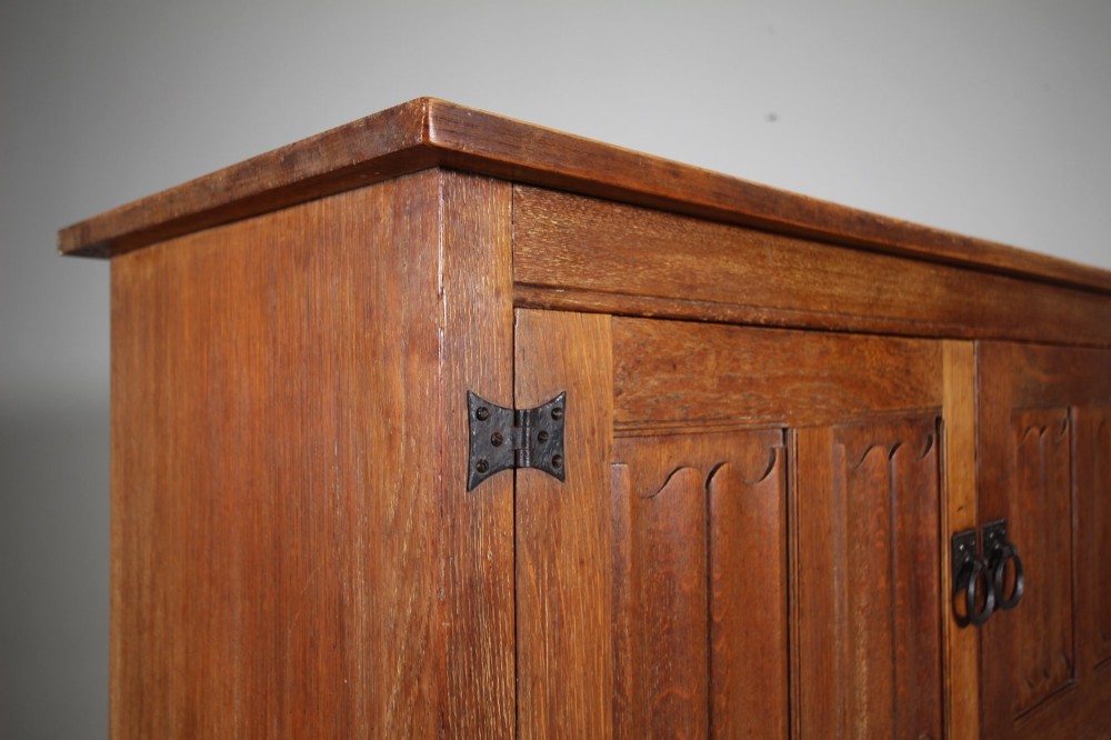 A 19th-century oak dresser base featuring two carved linenfold panel doors, iron drop handles, a single lower drawer, and carved plank supports. View VIII