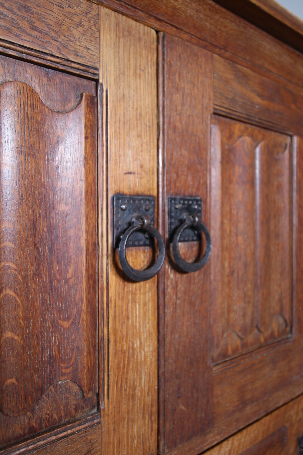 A 19th-century oak dresser base featuring two carved linenfold panel doors, iron drop handles, a single lower drawer, and carved plank supports. View X