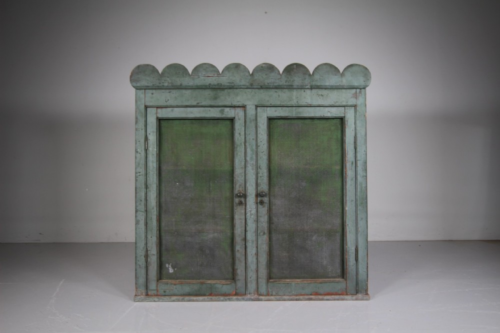 A large Georgian pine food safe in distressed sage green paint featuring a scalloped top pediment and wire mesh double doors. View VII