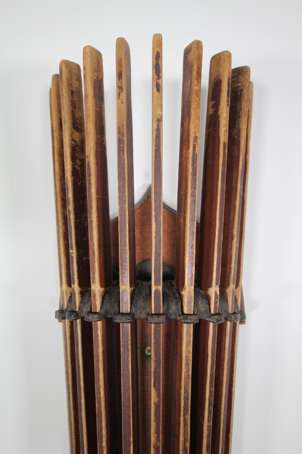 An antique wall-mounted wooden clothes dryer featuring multiple moveable laths fanning out from a central dark wood backplate. View V