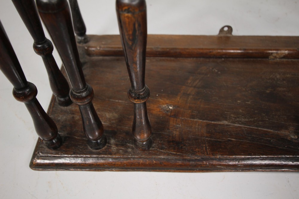 A 17th-century dark oak wall-mounted livery cupboard featuring a rectangular frame enclosing closely set turned wooden spindles on all open sides. View III
