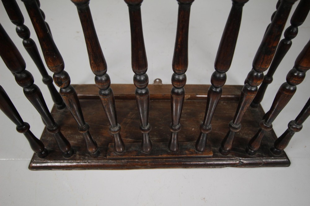 A 17th-century dark oak wall-mounted livery cupboard featuring a rectangular frame enclosing closely set turned wooden spindles on all open sides. View IV