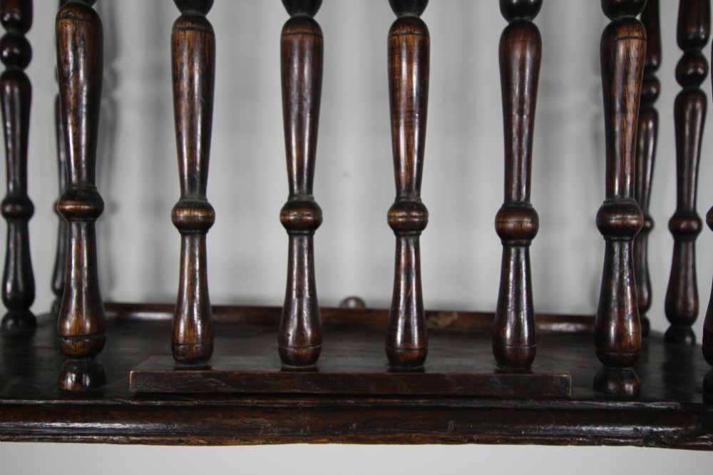A 17th-century dark oak wall-mounted livery cupboard featuring a rectangular frame enclosing closely set turned wooden spindles on all open sides. View VII