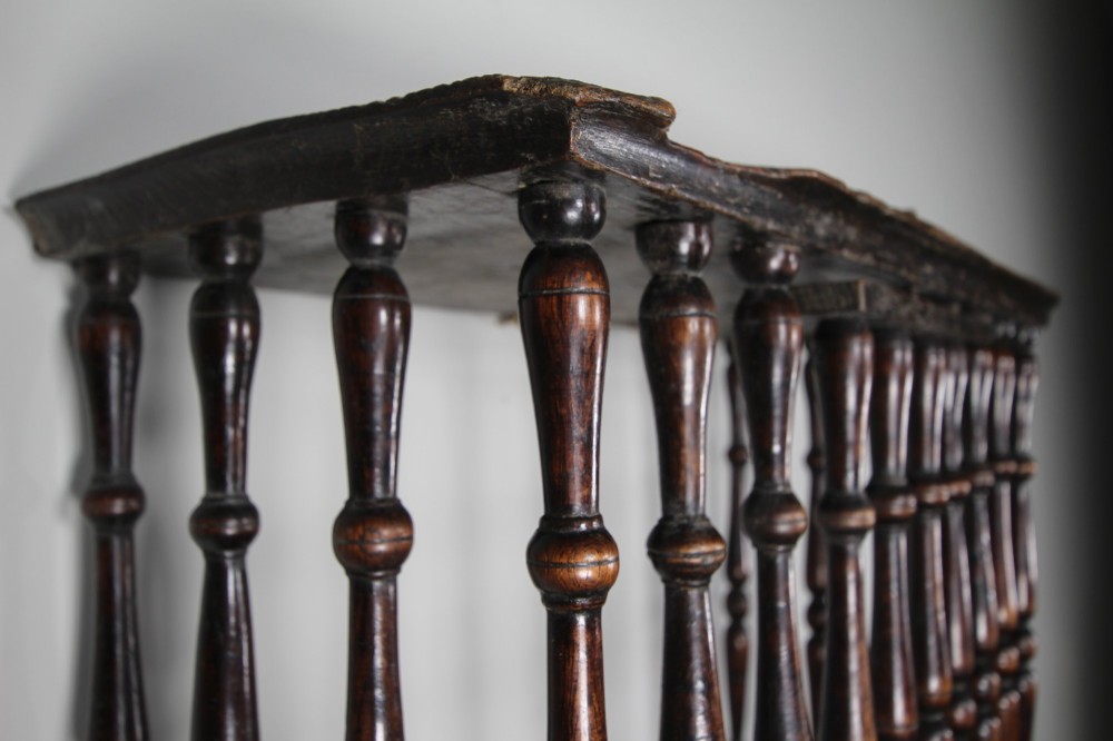 A 17th-century dark oak wall-mounted livery cupboard featuring a rectangular frame enclosing closely set turned wooden spindles on all open sides. View IX