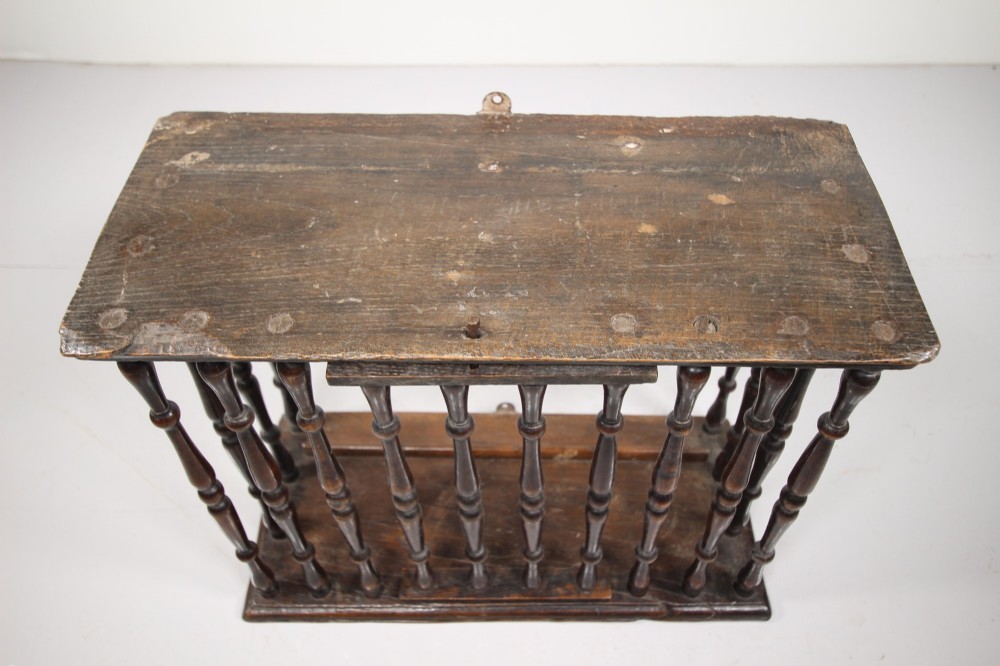 A 17th-century dark oak wall-mounted livery cupboard featuring a rectangular frame enclosing closely set turned wooden spindles on all open sides. View XII