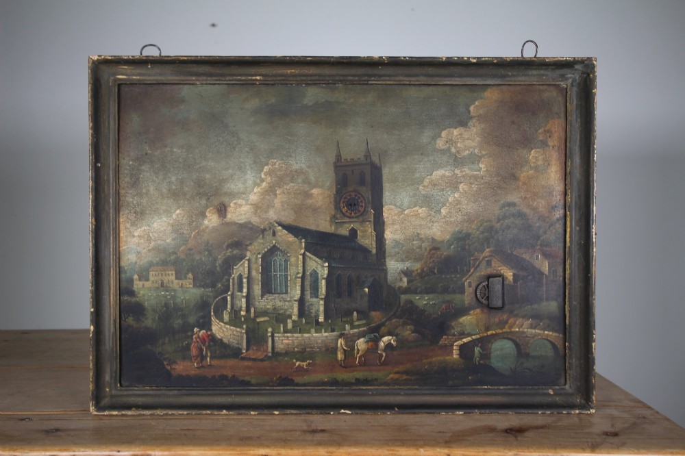 An 18th-century oil painting on tin depicting a church landscape with integrated mechanical clock hands and a visible waterwheel mechanism, enclosed in a dark wooden frame.
