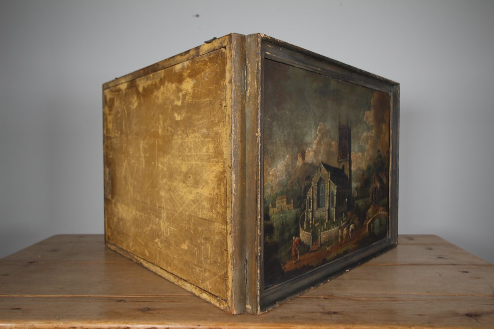 An 18th-century oil painting on tin depicting a church landscape with integrated mechanical clock hands and a visible waterwheel mechanism, enclosed in a dark wooden frame. View IV