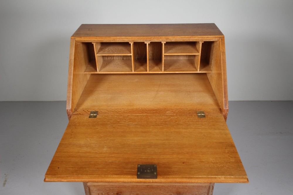 A 1920s oak writing bureau featuring a sloped fall-front desk above four drawers with turned wooden knobs, set on spherical bun feet. View V