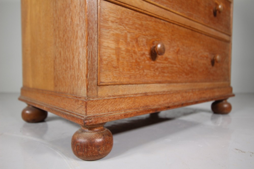 A 1920s oak writing bureau featuring a sloped fall-front desk above four drawers with turned wooden knobs, set on spherical bun feet. View VIII