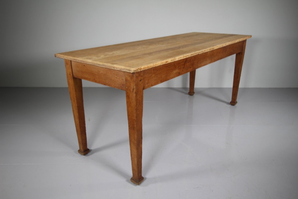 An English Edwardian antique oak dining table featuring a rectangular plank top and four square tapered legs.