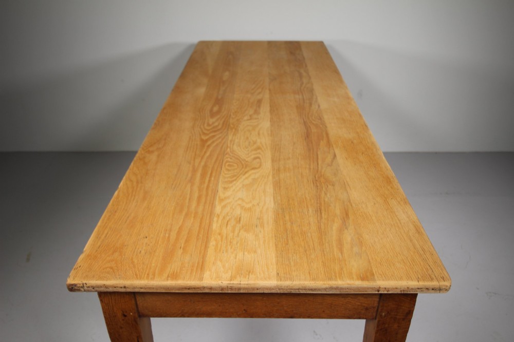 An English Edwardian antique oak dining table featuring a rectangular plank top and four square tapered legs. View II
