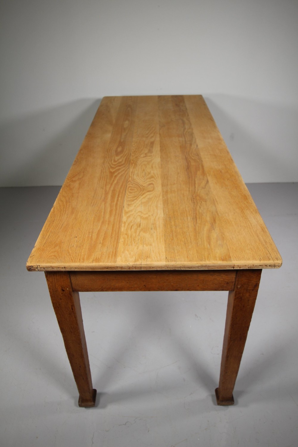 An English Edwardian antique oak dining table featuring a rectangular plank top and four square tapered legs. View VI