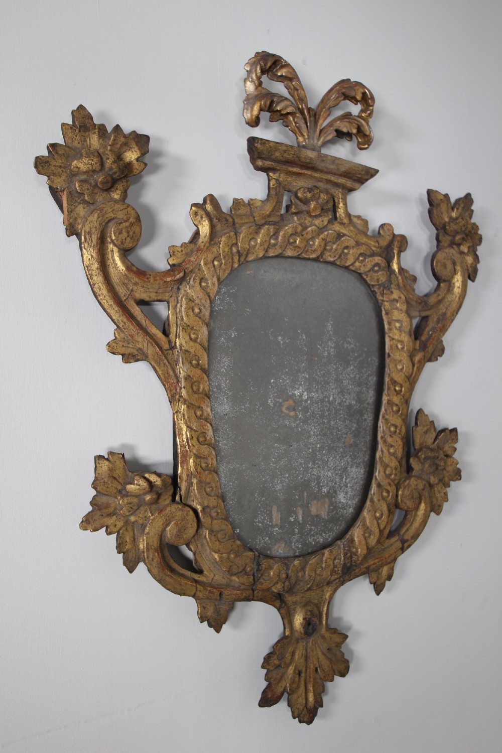 An 18th-century carved wood and gilt wall mirror featuring an ornate cartouche frame with acanthus leaf scrolls, rope twist trim, and a foxed mirror plate. View III