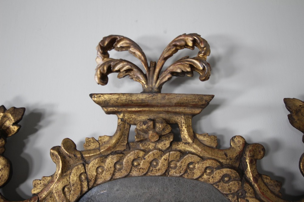 An 18th-century carved wood and gilt wall mirror featuring an ornate cartouche frame with acanthus leaf scrolls, rope twist trim, and a foxed mirror plate. View VI