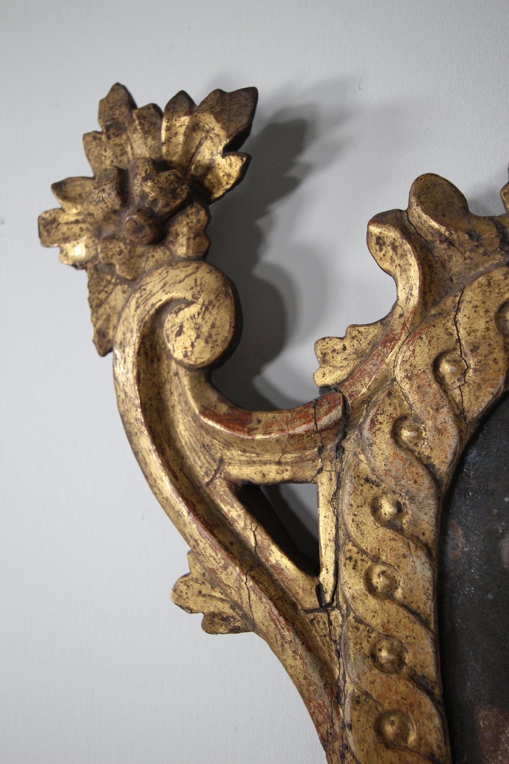An 18th-century carved wood and gilt wall mirror featuring an ornate cartouche frame with acanthus leaf scrolls, rope twist trim, and a foxed mirror plate. View VII