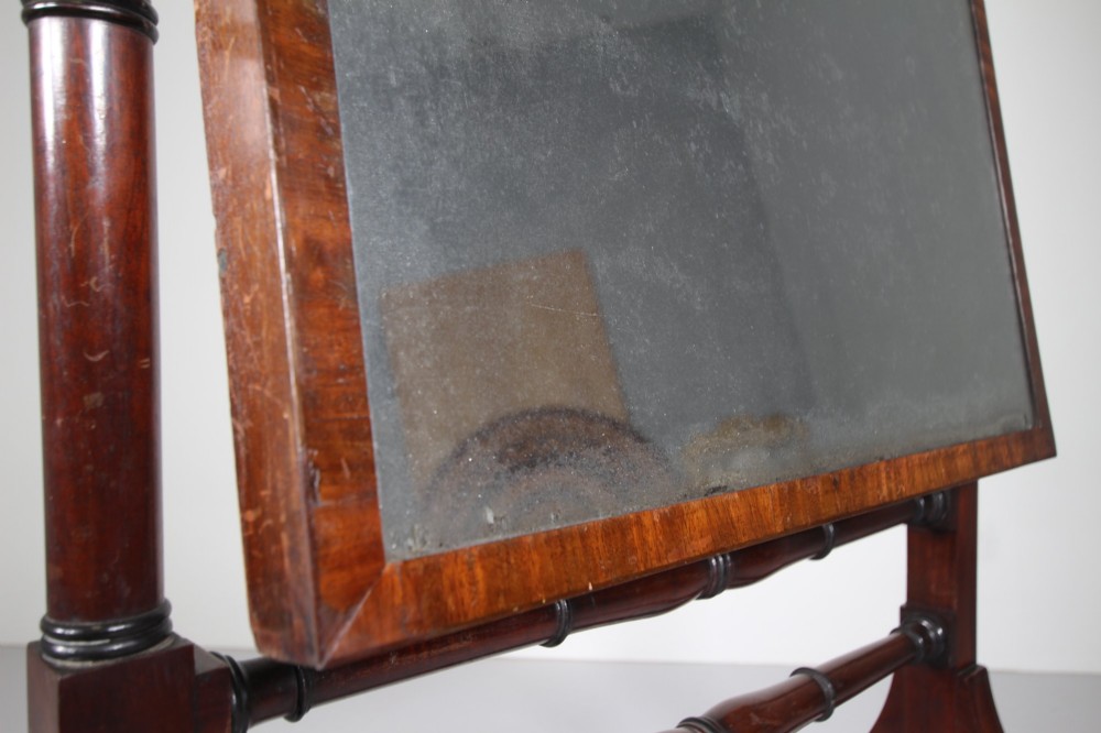 An English Regency mahogany cheval mirror featuring a rectangular tilting glass plate supported by turned uprights and splayed legs with brass paw castors. View II