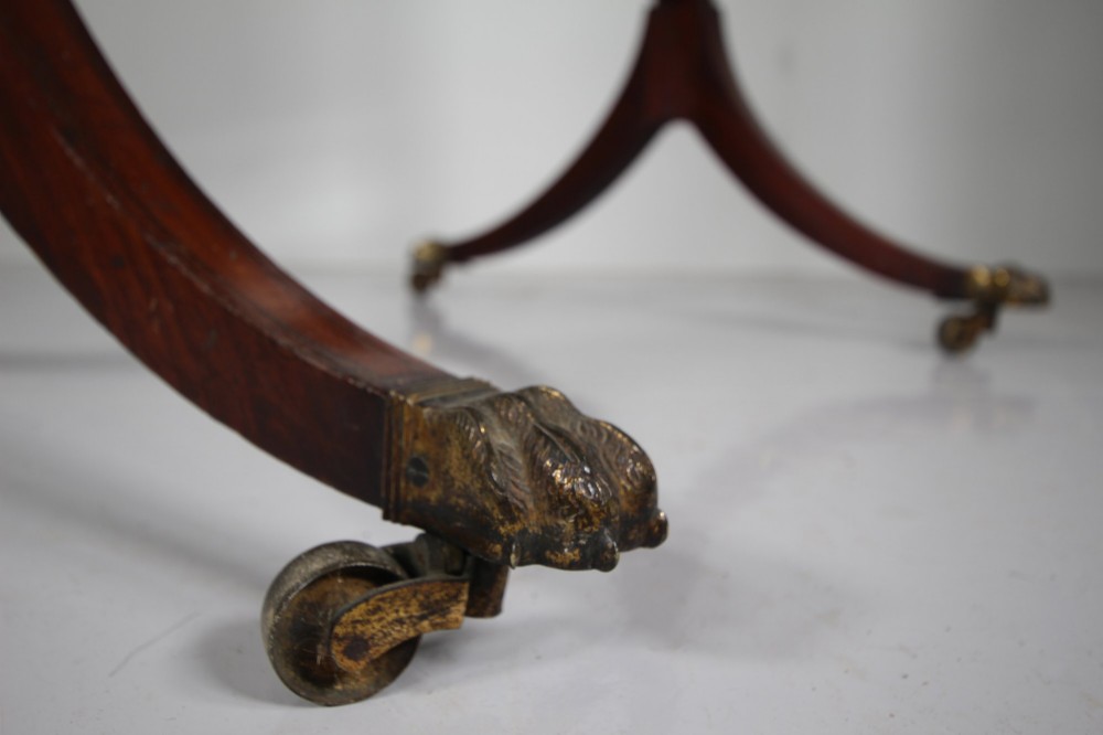 An English Regency mahogany cheval mirror featuring a rectangular tilting glass plate supported by turned uprights and splayed legs with brass paw castors. View VI