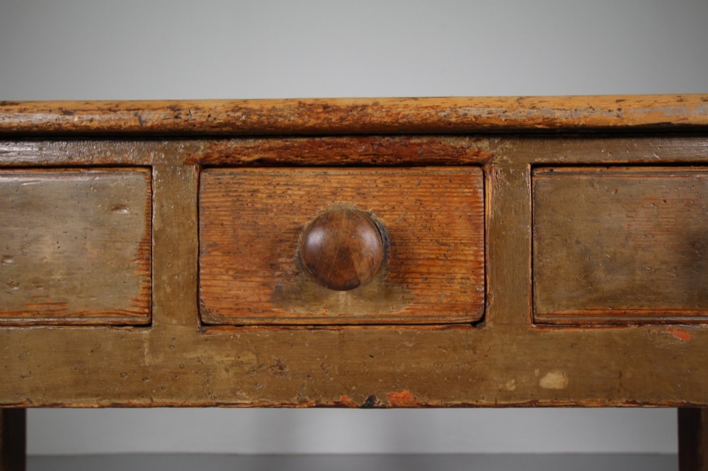 An 18th-century English painted pine serving table featuring three drawers with wooden handles, a shaped apron, and tapered square legs. View V