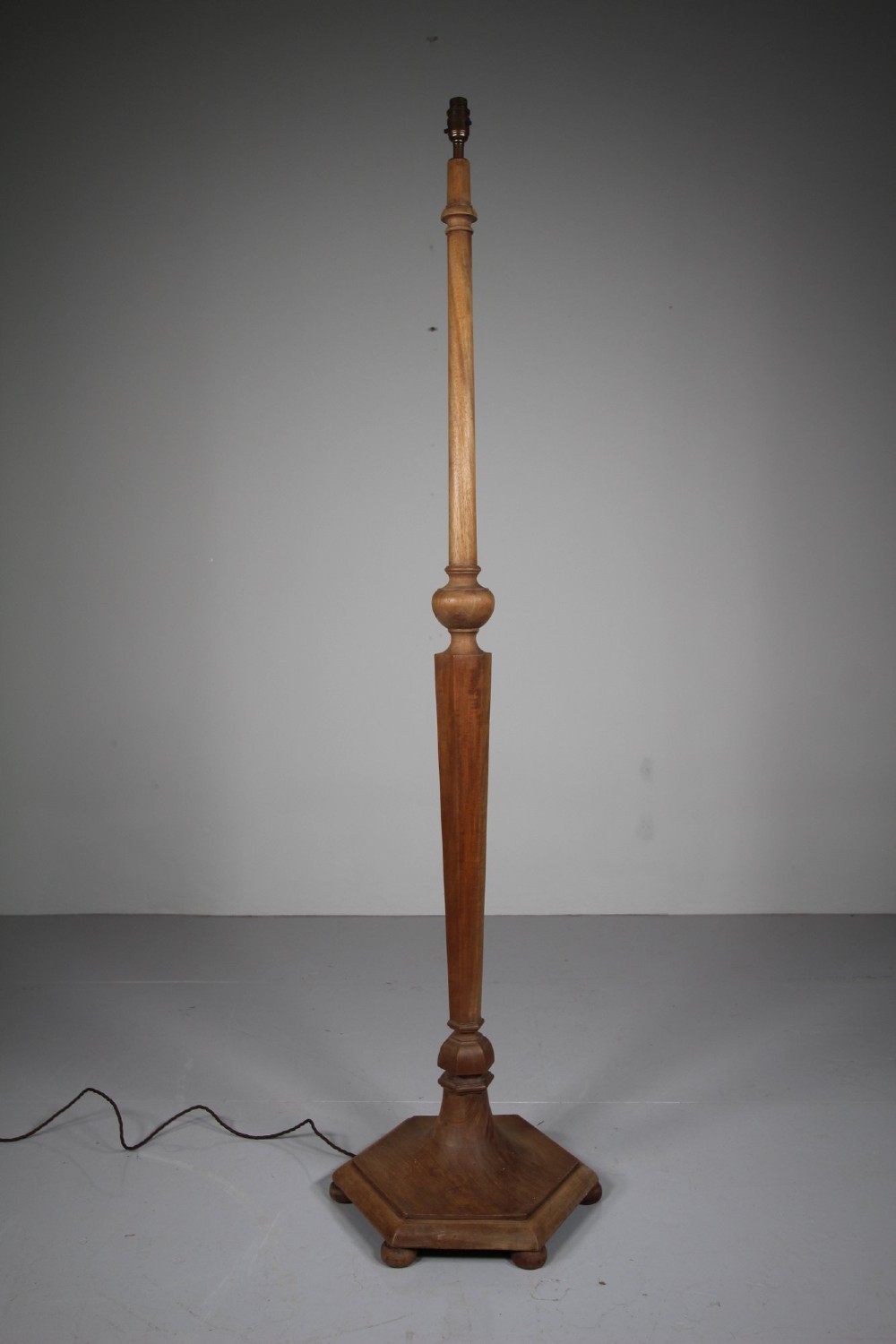 A 1930s turned walnut floor lamp featuring a tapered column resting on a moulded hexagonal base with bun feet.