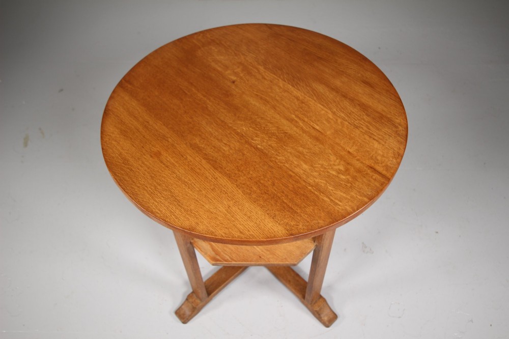 A circular antique oak side table featuring an intermediate lower shelf and an X-frame base stretcher. View V