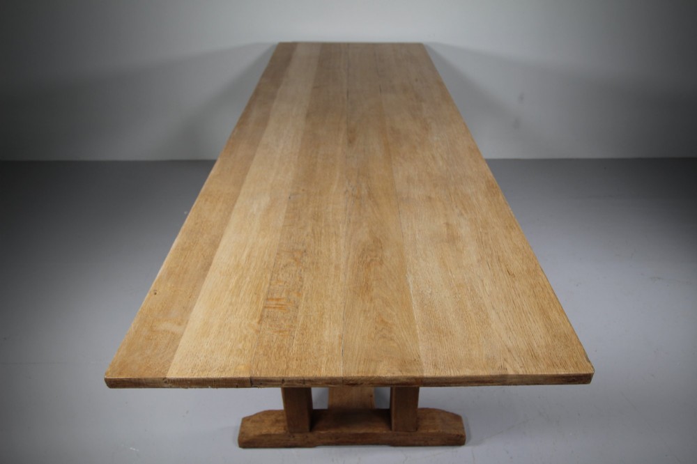 A 1930s solid oak refectory dining table featuring a rectangular top set over double column trestle ends and a low central stretcher. View III