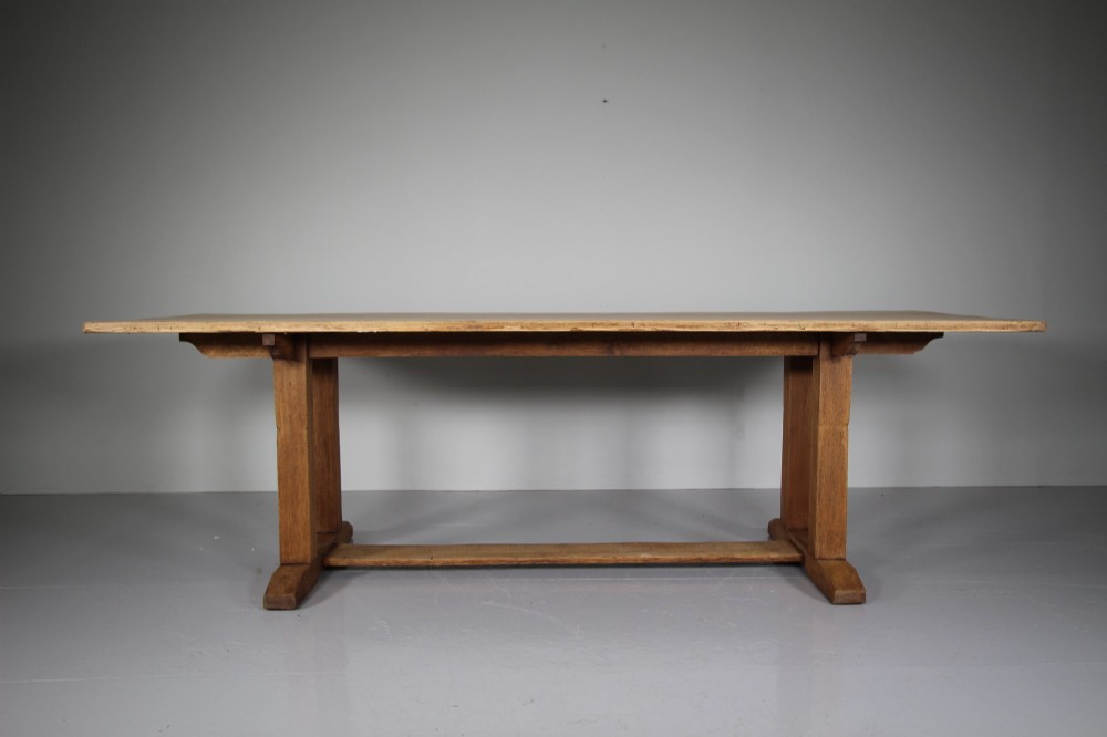 A 1930s solid oak refectory dining table featuring a rectangular top set over double column trestle ends and a low central stretcher. View V