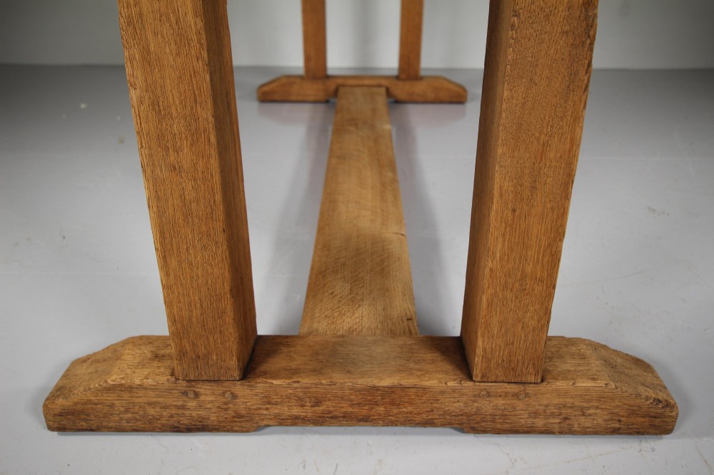 A 1930s solid oak refectory dining table featuring a rectangular top set over double column trestle ends and a low central stretcher. View VIII