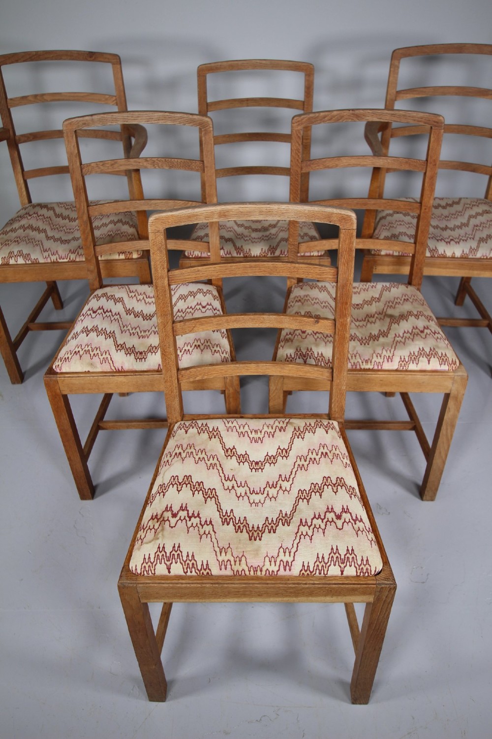 A set of six 1920s oak dining chairs including two armchairs, featuring structured horizontal ladder backs and patterned fabric upholstered seats. View II